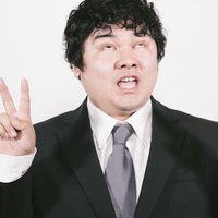 どうにでもなーれ、白目を向いてダブルピースするスーツ姿の男性の写真
