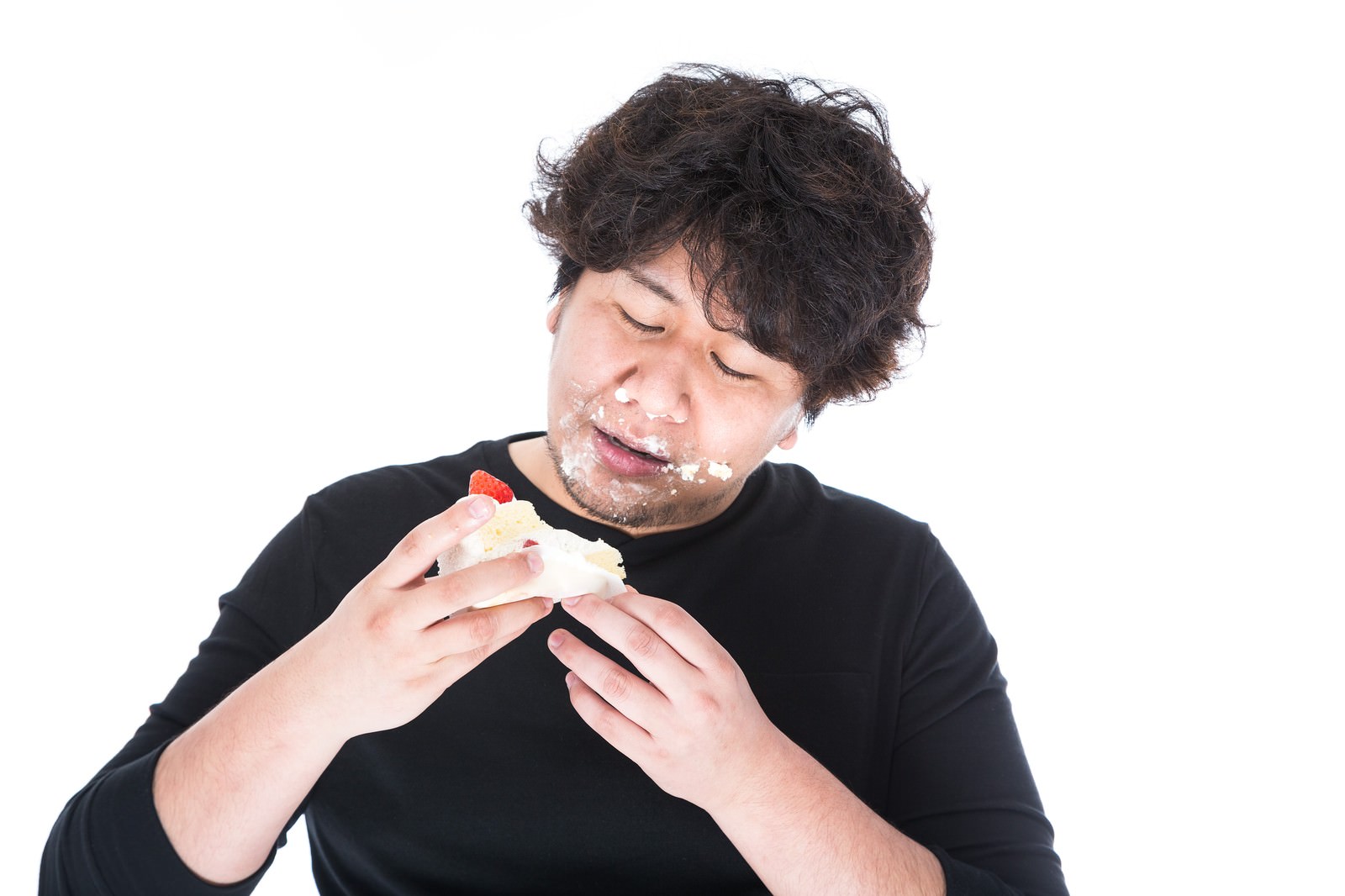 ケーキを両手で持ち、クリームまみれで食べている男性の顔と上半身［モデル：あまのじゃく］