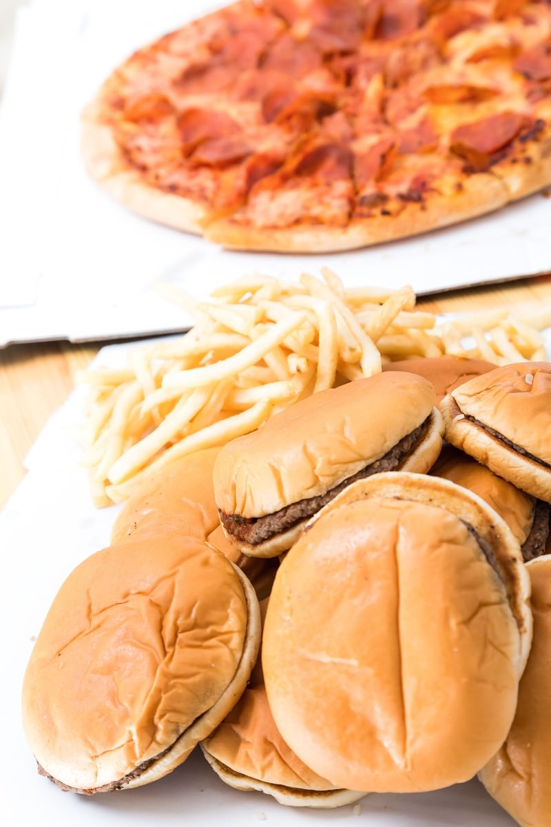 ハンバーガー、ピザ、ポテトフライが白い背景に並んでいる
