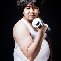 完全個室のプライベートジムで初トレーニング。ダンベルを握る男性の写真
