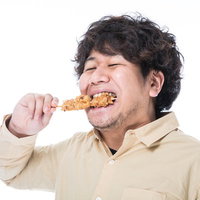 から揚げ棒を食べて気分が上がるコンビニマニアの男性の写真