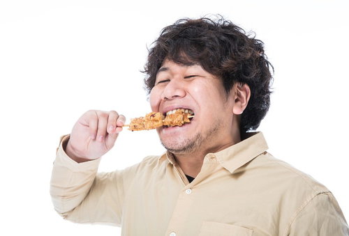 から揚げ棒を食べて気分が上がるコンビニマニアの男性の写真