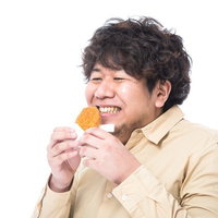 熱々のコロッケをほおばる男性メディアコンサルタントの写真