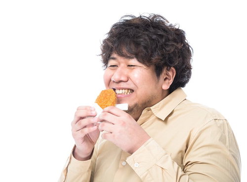 熱々のコロッケをほおばる男性メディアコンサルタントの写真