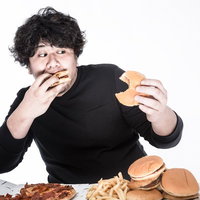 左右左右BAのリズムでハンバーガーを食べる男性ゲーマーの写真