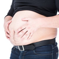 ハンドパワーで腹部をへこませようとする肥満男性の写真