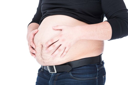 ハンドパワーで腹部をへこませようとする肥満男性の写真