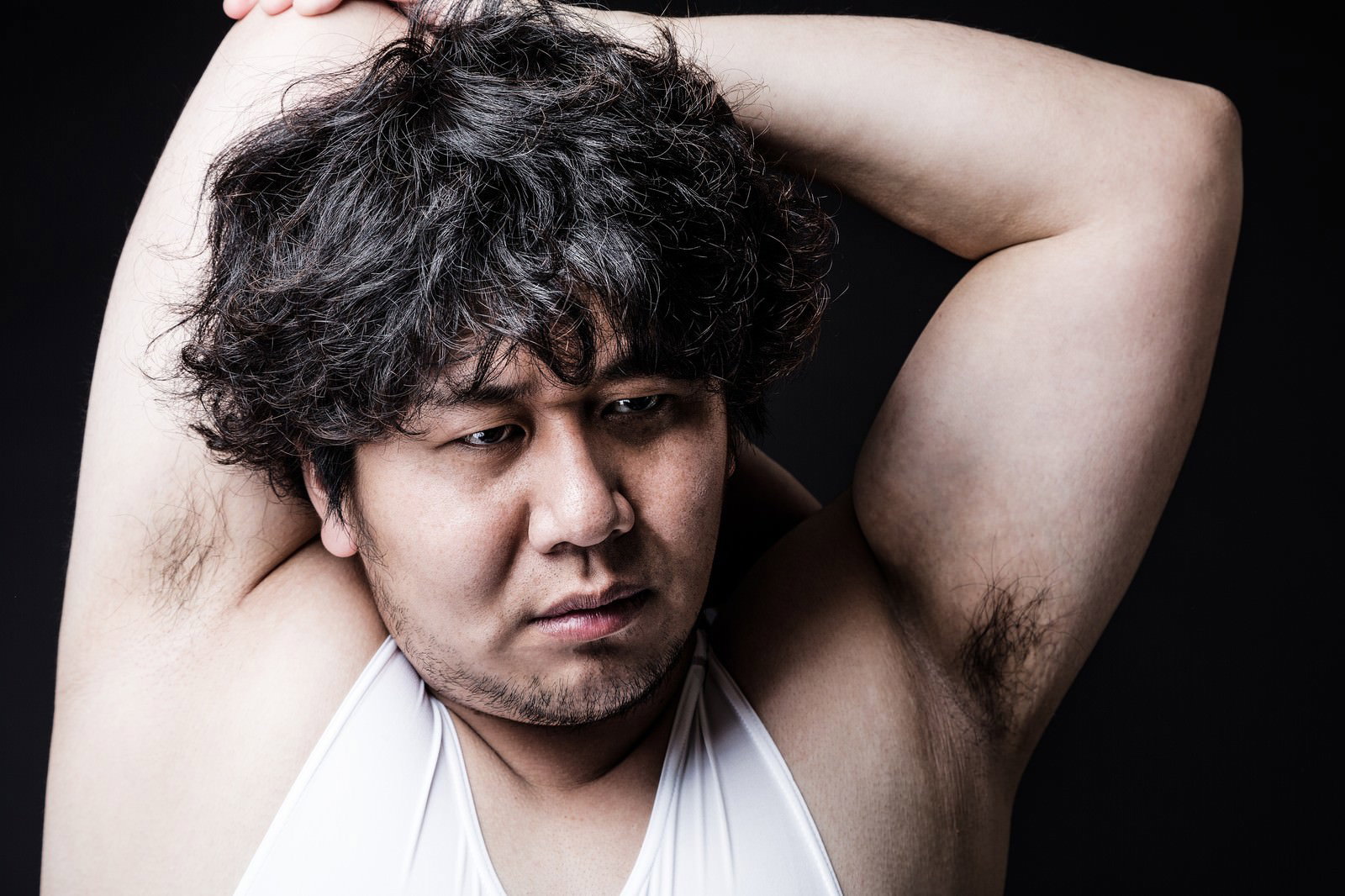 白いシャツを着たぽっちゃり体型の男性が、両腕を上げて背中を反らしてストレッチしている［モデル：あまのじゃく］