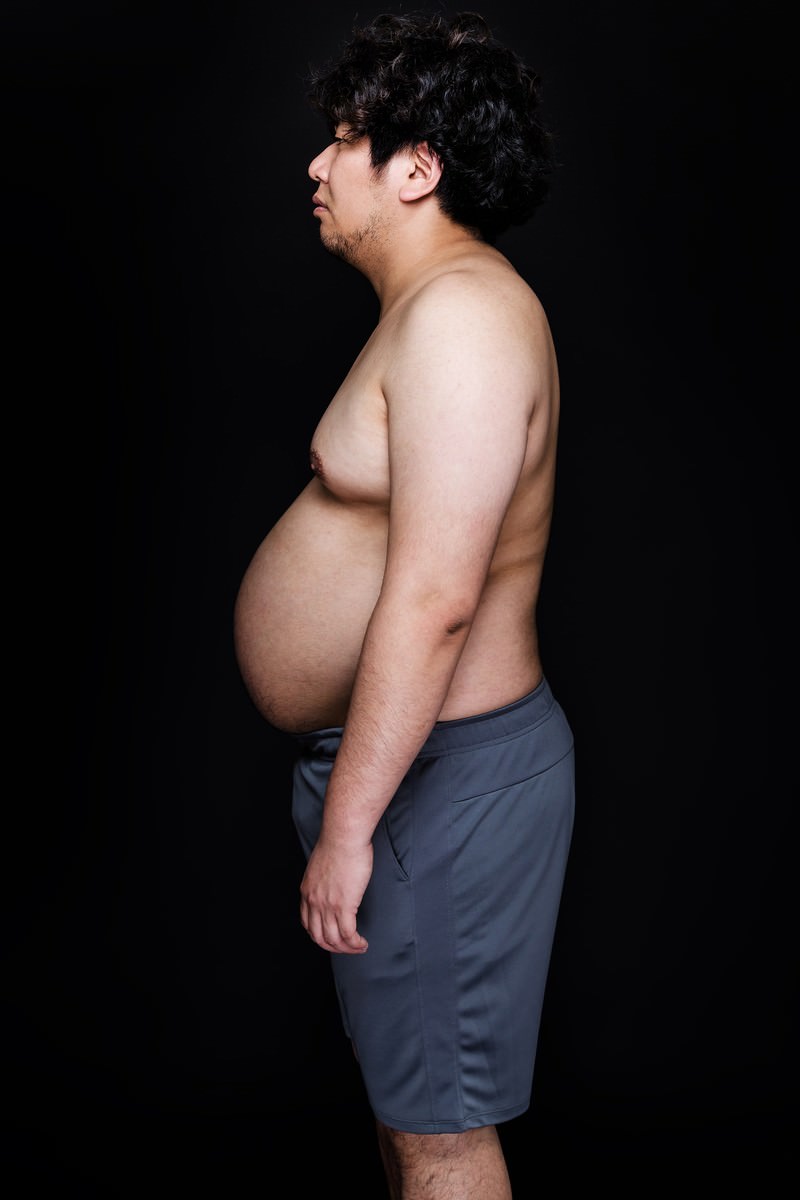 体重100kg超の男性が横向きで立ち、ぽっこりと膨らんだお腹を見せている［モデル：朽木誠一郎］
