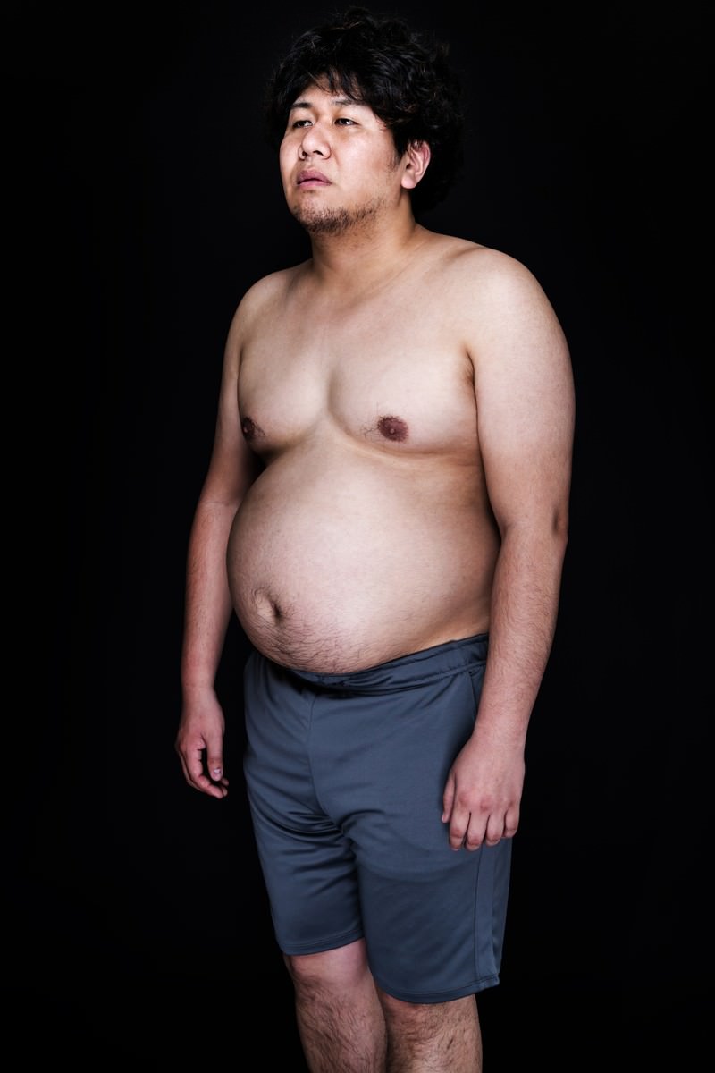 食事制限中にジャンクフードへの誘惑に抗えない男性が遠い目をしている［モデル：朽木誠一郎］