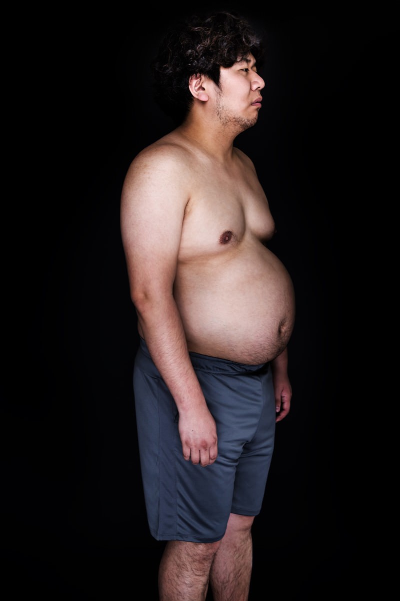 ぽっちゃり体型の男性が横向きで右前を見つめる写真［モデル：朽木誠一郎］
