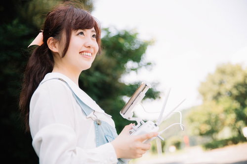 ドローンを操縦するタブレット片手の女性（ちょっとまぶしい）