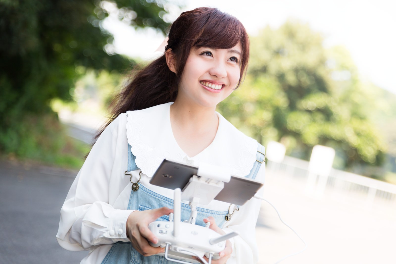 ドローンのコントローラーを持って笑顔の女性［モデル：河村友歌］
