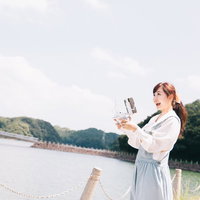 伊万里市の河畔でタブレットを使ってドローンを操縦する女性の写真