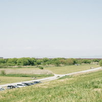 古河市の河川敷にあるドローン練習場の広々とした草地と舗装道路の写真
