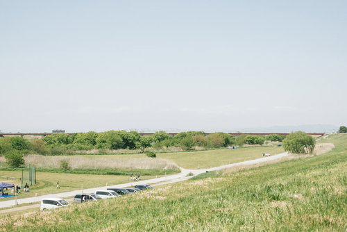 古河市の河川敷にあるドローン練習場の広々とした草地と舗装道路