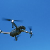 青空を飛行するドローン（Mavic）の空撮映像の写真