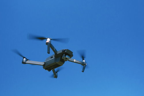 青空を飛行するドローン（Mavic）の空撮映像