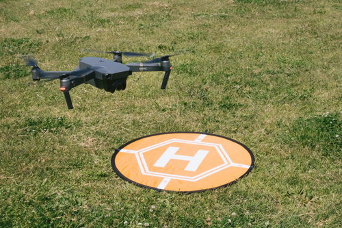 芝生に着陸した黒いドローンとオレンジ色のランディングパッド