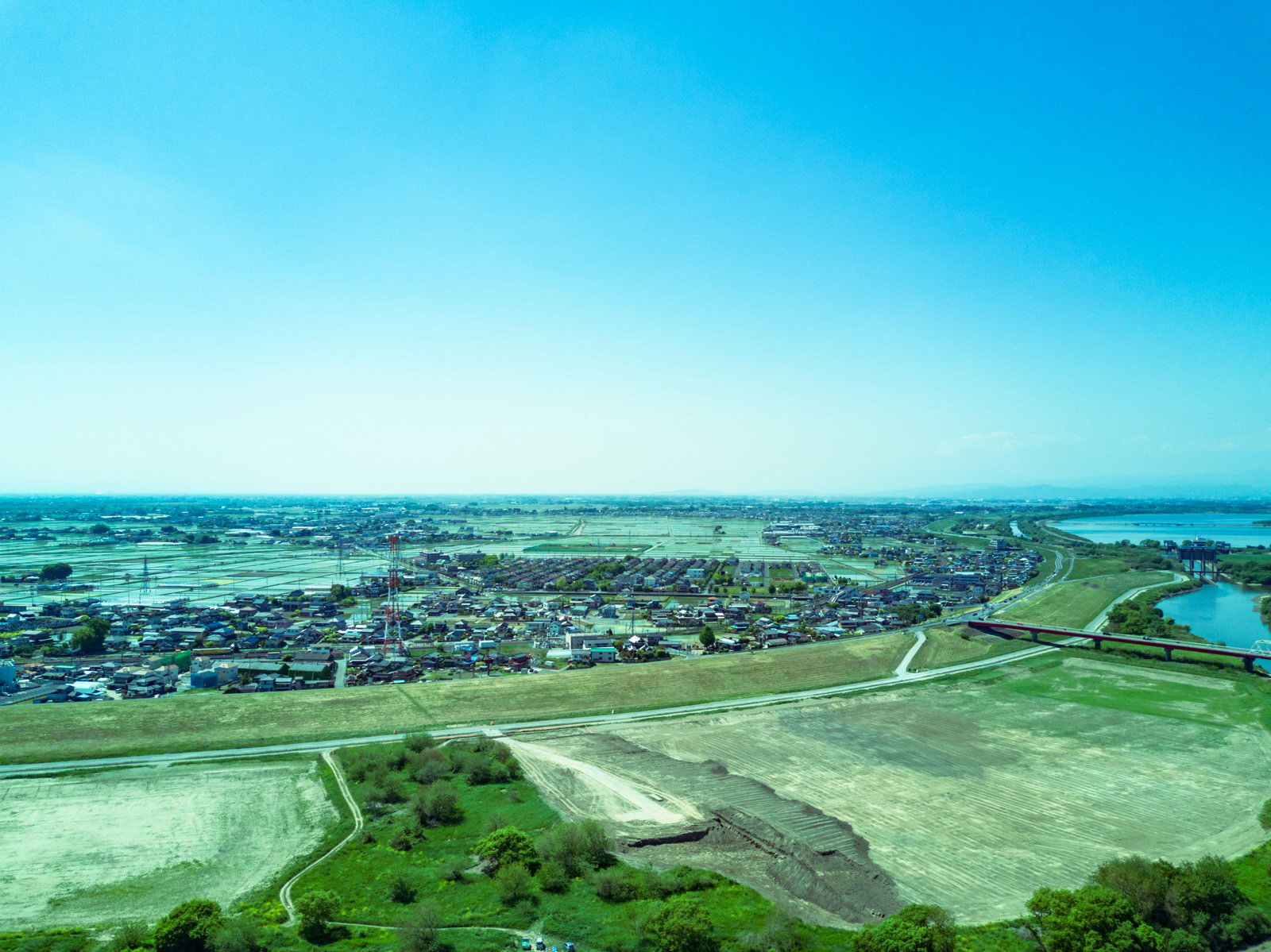 青空の下に広がる渡良瀬川の河川敷を空撮した風景