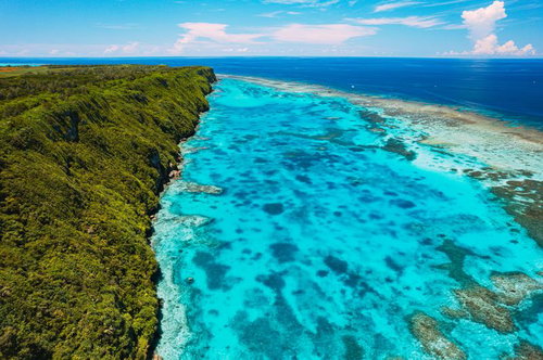 断崖絶壁の伊良部島三角点を囲む宮古ブルーの海（空撮）