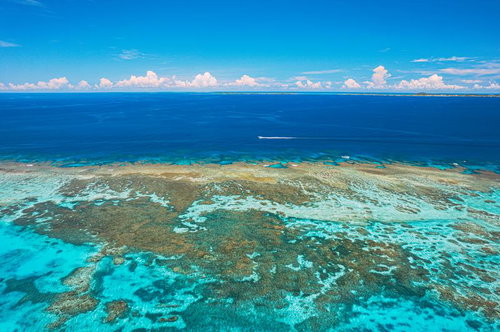 伊良部島の三角点を望む宮古ブルーの海岸と岩礁