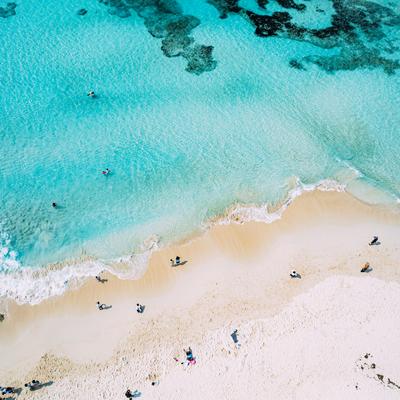 砂山ビーチ上空からの俯瞰、透明な海に浮かぶ海水浴客の写真