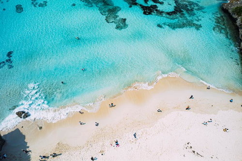 砂山ビーチ上空からの俯瞰、透明な海に浮かぶ海水浴客