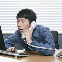 自社の著作権侵害をチェックする担当者が電話で対応の写真