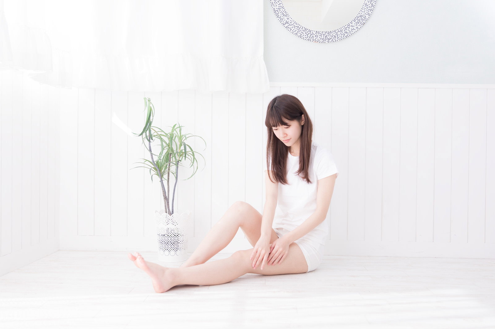 白いトップスを着た女性が座って両手で太ももを触っている様子［モデル：川子芹菜］