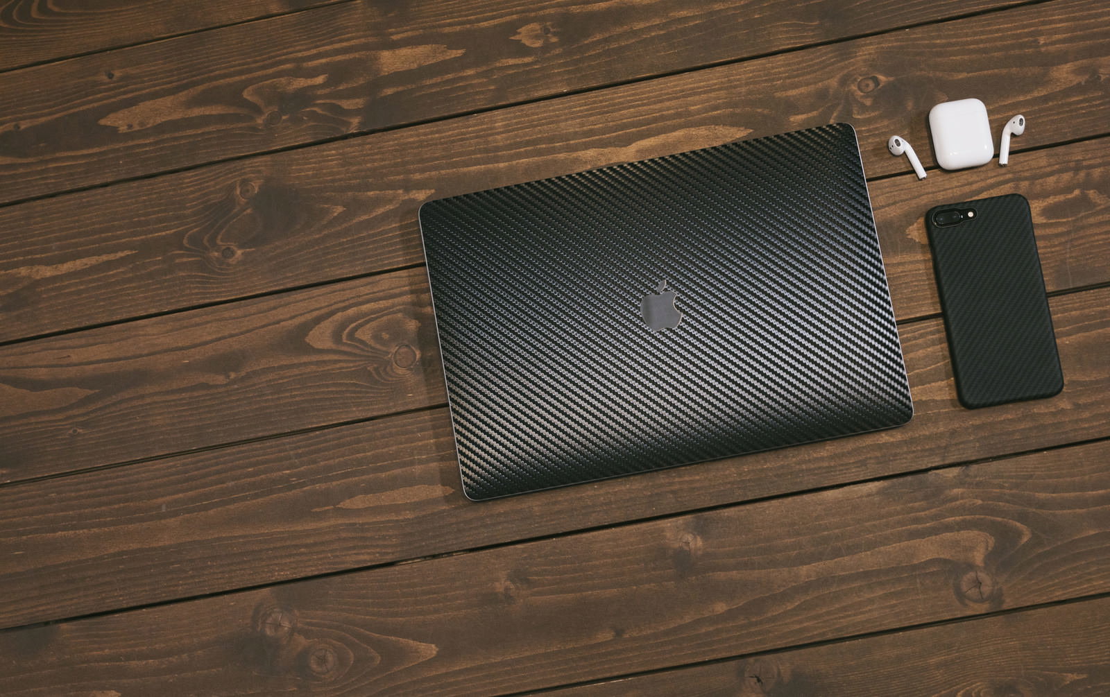 木目テーブルの上に置かれたMacBookとiPhoneとAirPods