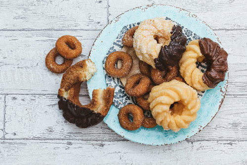 白い皿から溢れ出るカラフルなドーナッツとおやつ