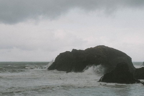 雲間からのぞく青空とは裏腹に横殴りの雨が降る荒れた海の景色