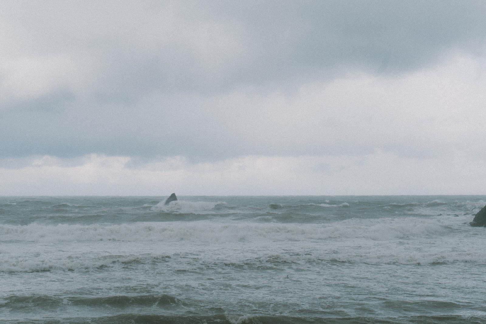 曇り空の下で高波が岩礁に激しく打ち付けている荒れた日本海