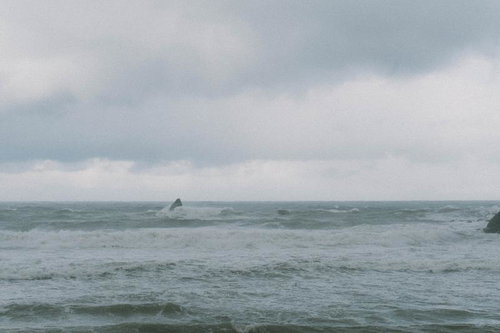 荒れた日本海で高波に包まれる岩礁の写真