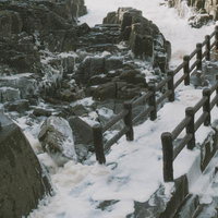 日本海の荒波と波の花が覆う遊歩道の写真