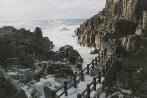 荒れた海が咲かせる波の花が寄せる岩場や歩道