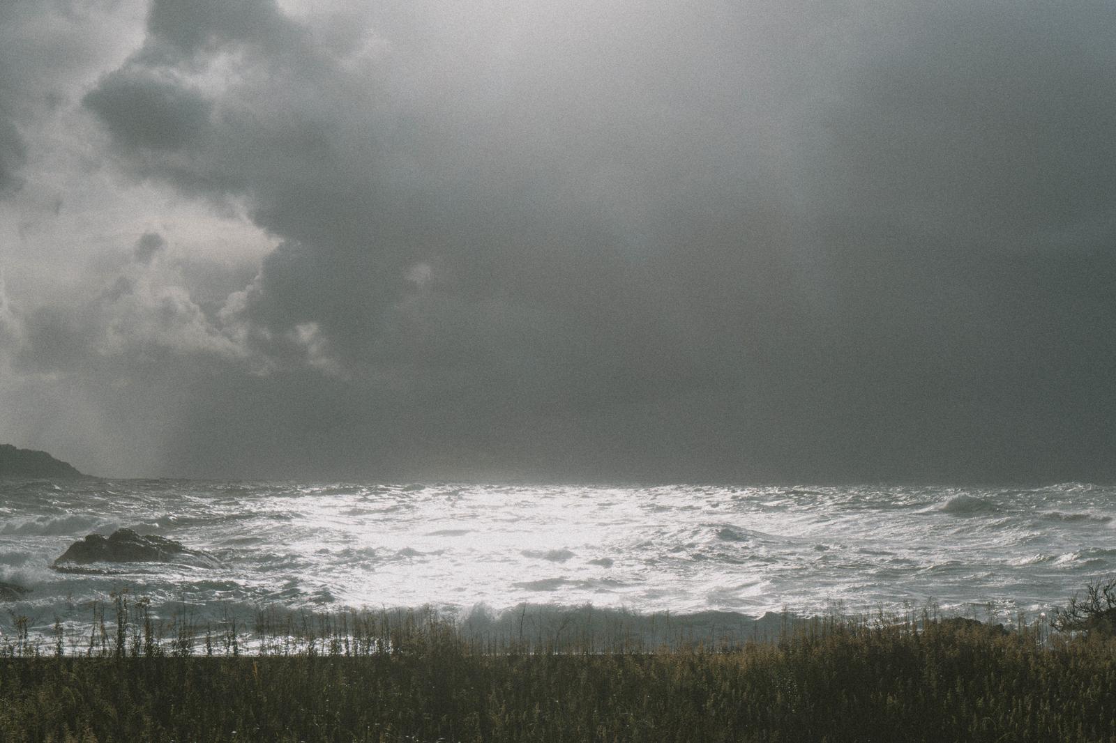 冬の日本海が時化ている海岸で、暗い雲と白い波が打ち寄せている風景