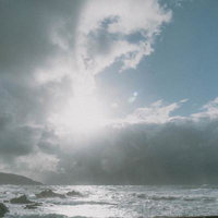 雲の切れ間から届く光に照らされる冬の日本海の写真