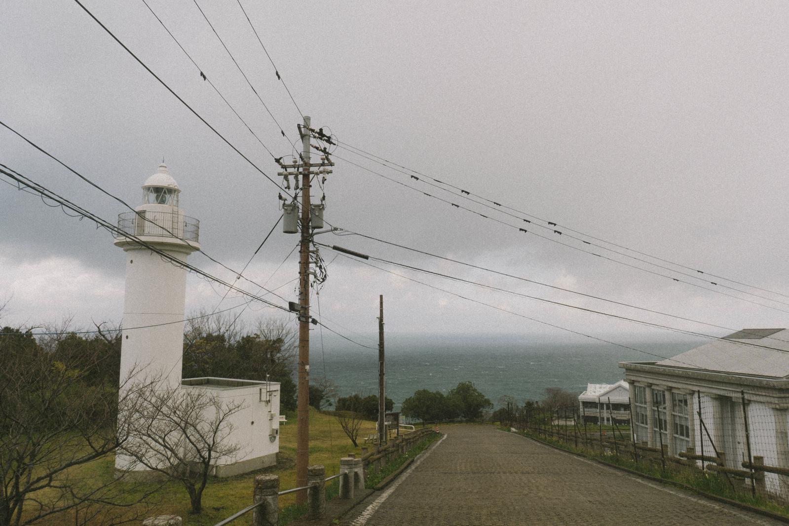 白い灯台と電柱が立つ坂道から見た日本海の風景