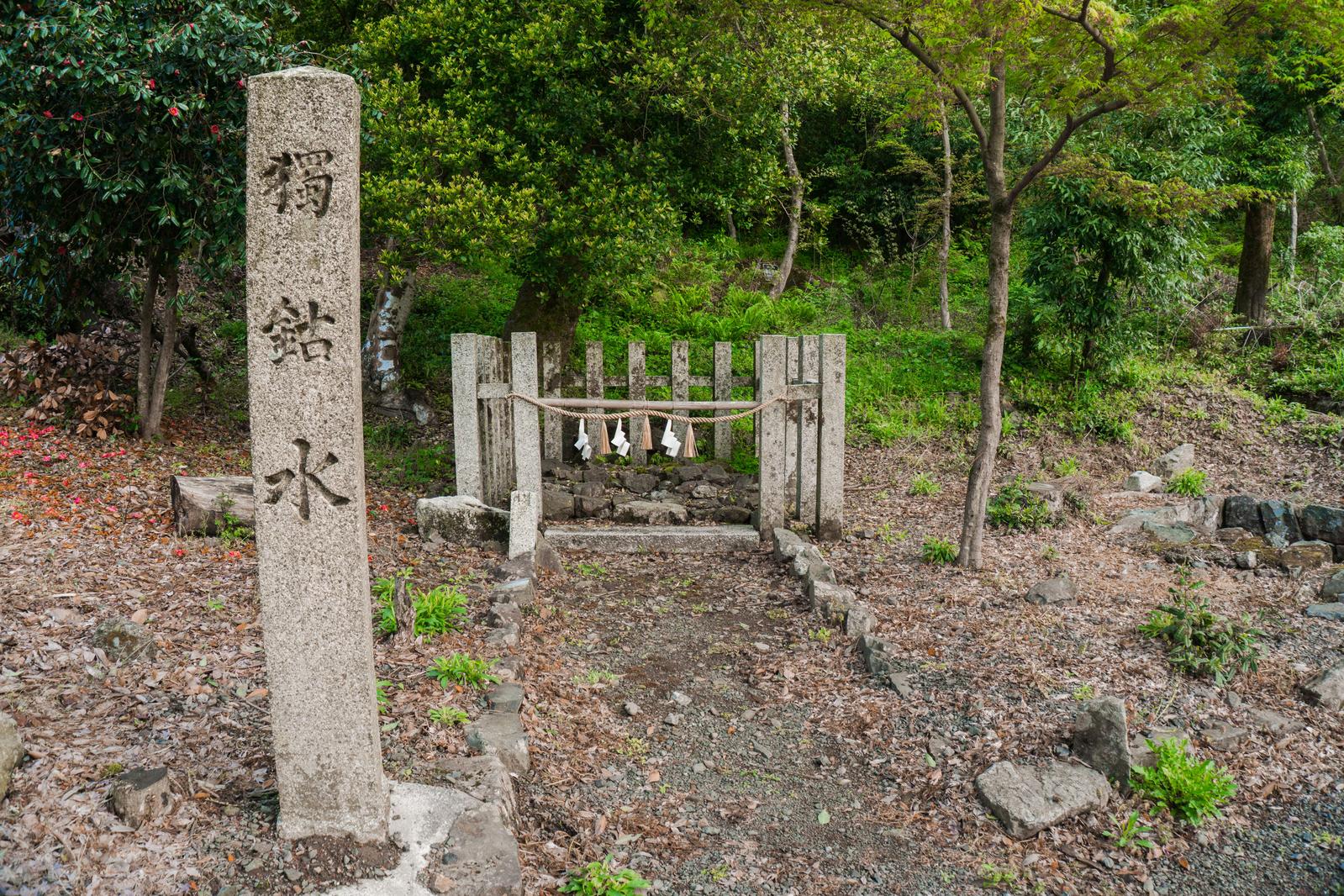 伊香具神社の境内に湧く独鈷水。石碑と木製の社が緑の森に囲まれている