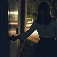 深夜に倉庫の扉を開ける女性の後ろ姿の写真