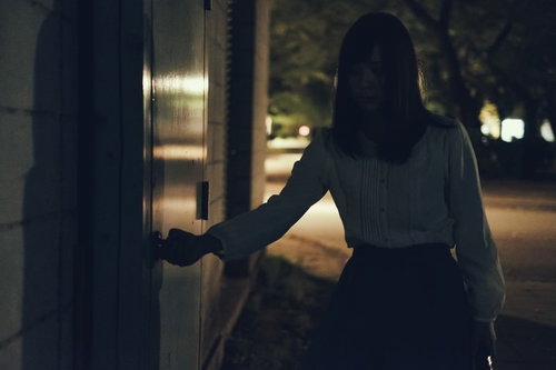 深夜に倉庫の扉を開ける女性の後ろ姿