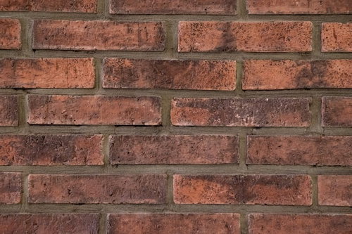 古びた赤褐色のレンガの壁のテクスチャーと石造モルタル