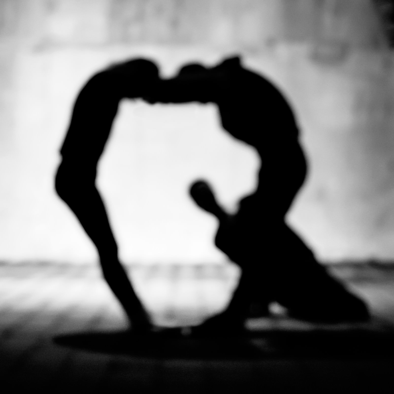 2人の人物がシルエットで体を使ってアルファベットQを作っている人文字のモノクロ写真