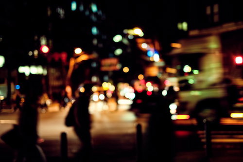 帰宅者と交通量の多い夜間の大通り、信号とヘッドライトの夜景