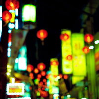 夜の繁華街に灯るネオンの看板と赤提灯が密集する風景の写真