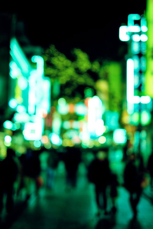 夜間の歓楽街を行き交う人々とネオン看板の夜景