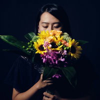 花束を持ち目を閉じる沈黙の中の女性の写真