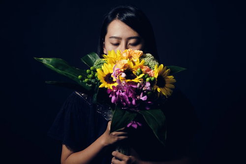 花束を持ち目を閉じる沈黙の中の女性